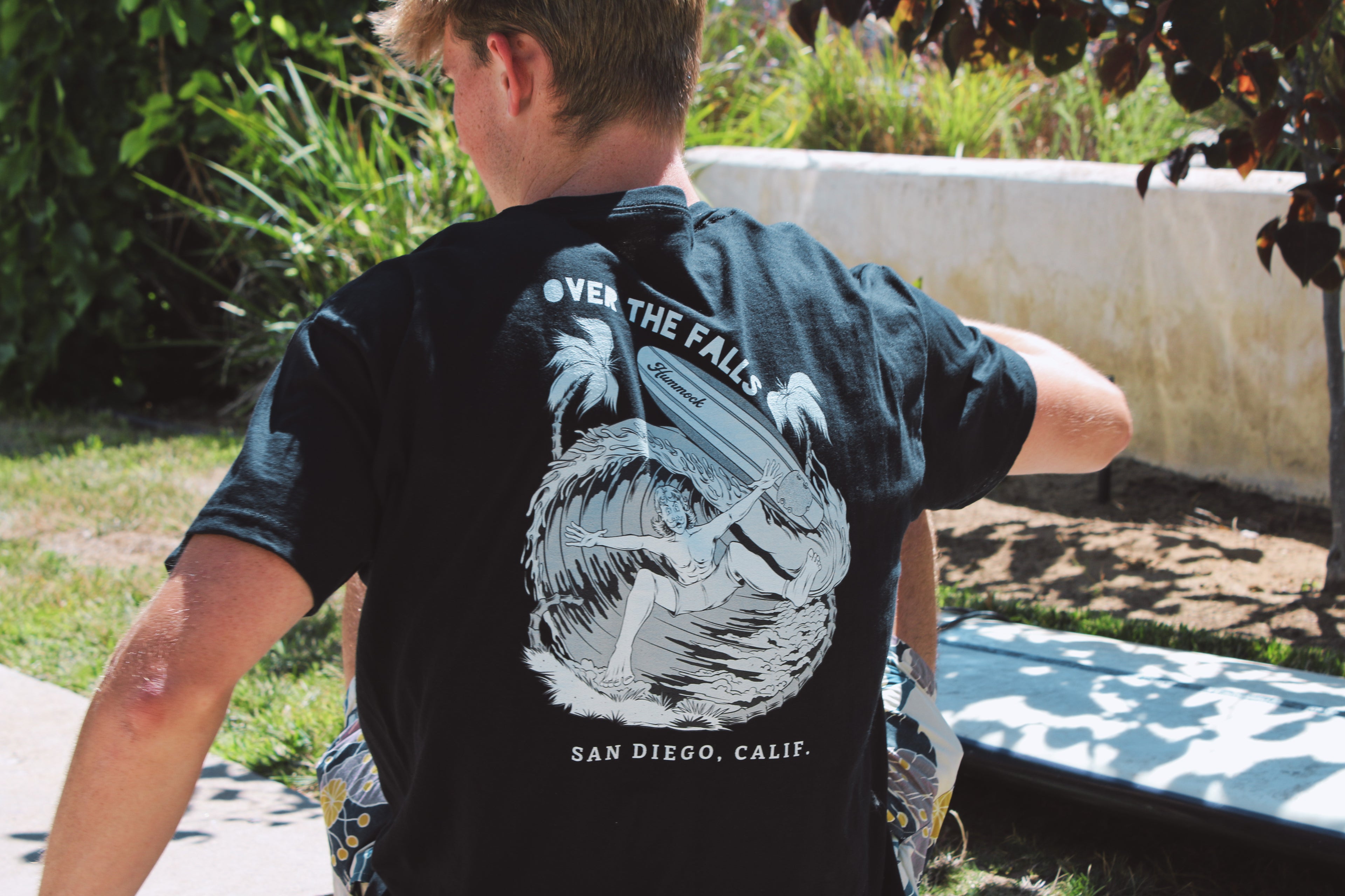 Person wearing a black t-shirt with 'Over the Falls' graphic and text, standing outdoors.